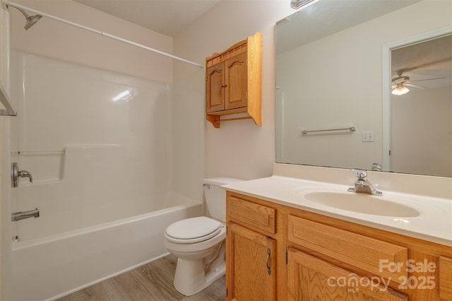 bathroom with ceiling fan, bathtub / shower combination, wood finished floors, vanity, and toilet
