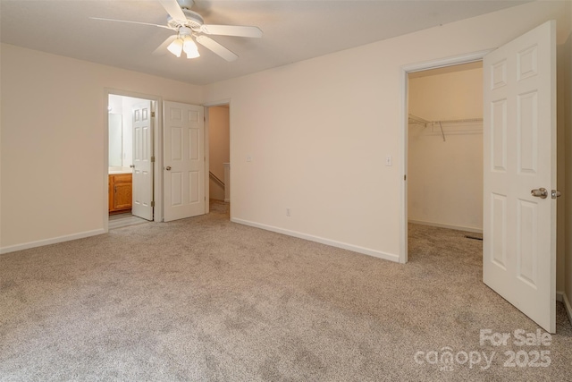 unfurnished bedroom featuring light colored carpet, baseboards, a spacious closet, and a closet