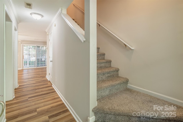 stairway featuring baseboards, wood finished floors, and visible vents