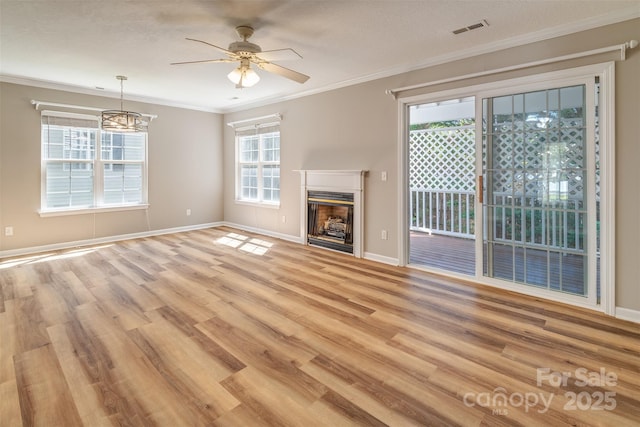 unfurnished living room featuring crown molding, light wood-style floors, ceiling fan with notable chandelier, baseboards, and visible vents