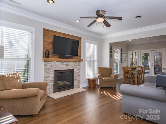 living area with a wealth of natural light, ceiling fan, visible vents, and wood finished floors