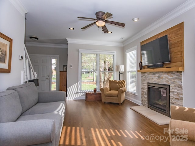 living room with a ceiling fan, a fireplace, crown molding, stairway, and wood finished floors