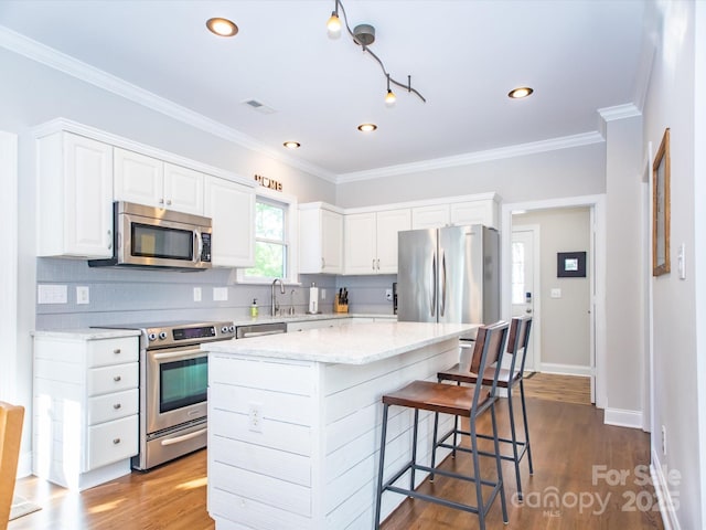 kitchen with dark wood-type flooring, tasteful backsplash, white cabinets, and stainless steel appliances