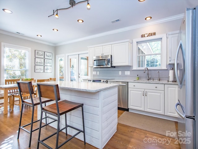 kitchen with a sink, visible vents, appliances with stainless steel finishes, and wood finished floors