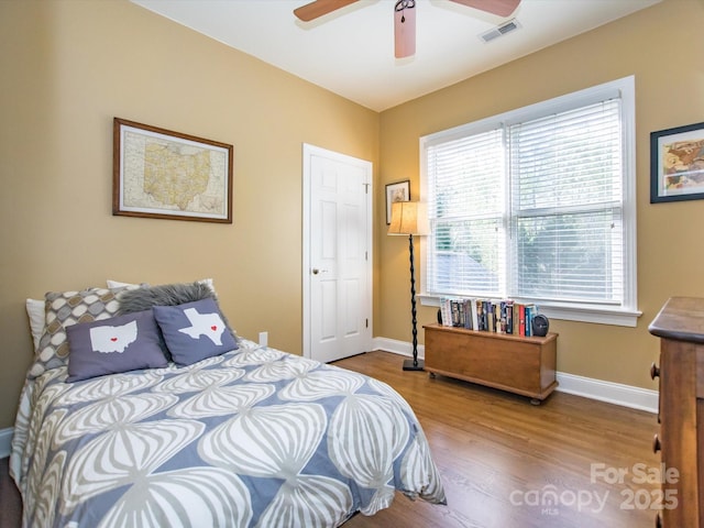 bedroom with visible vents, baseboards, ceiling fan, and wood finished floors
