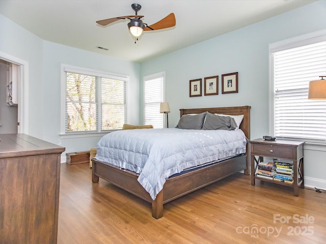 bedroom with visible vents, baseboards, a ceiling fan, and wood finished floors