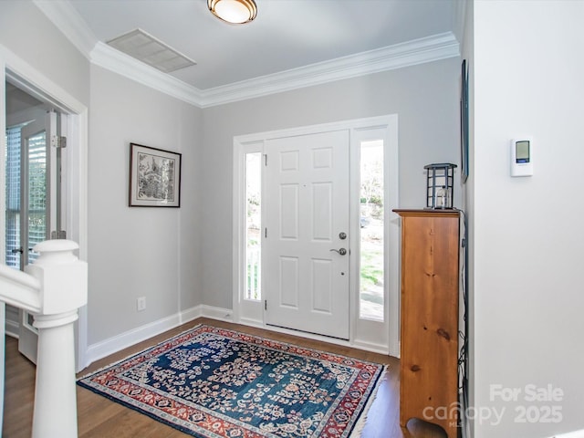entrance foyer featuring visible vents, baseboards, ornamental molding, and wood finished floors