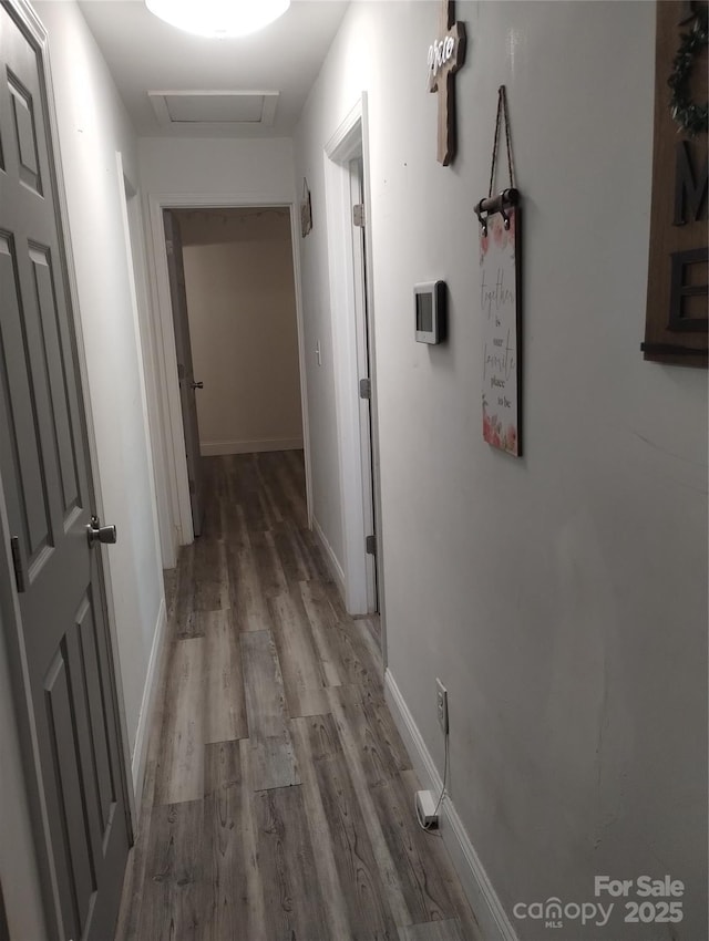 hallway with attic access, wood finished floors, and baseboards