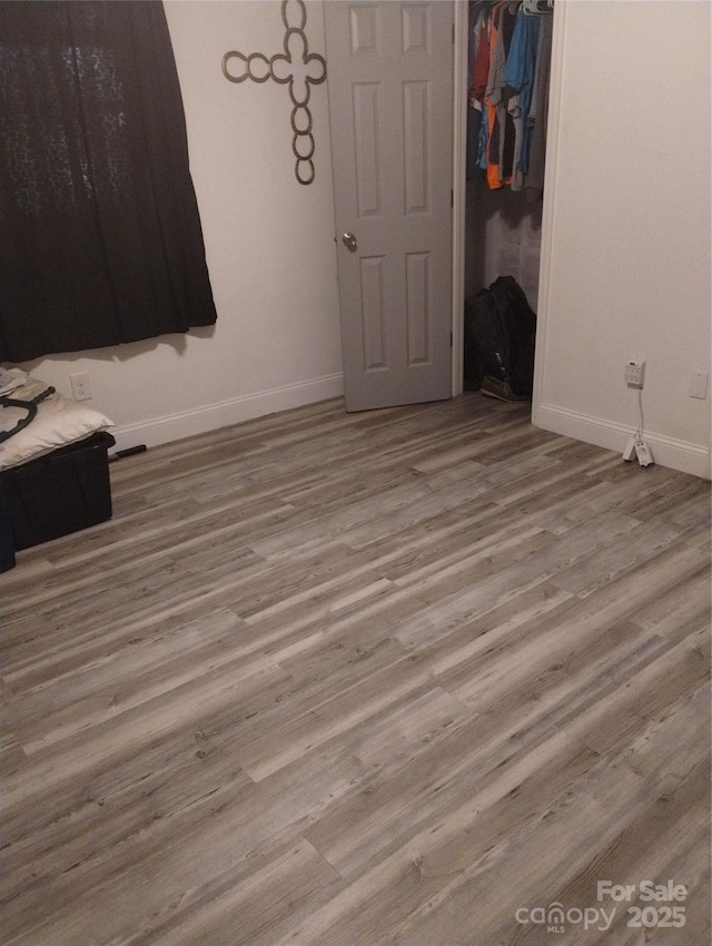 unfurnished bedroom with a closet, wood finished floors, and baseboards