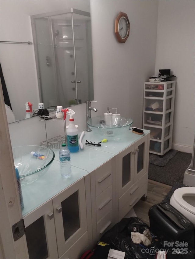 full bath featuring a stall shower, double vanity, and a sink