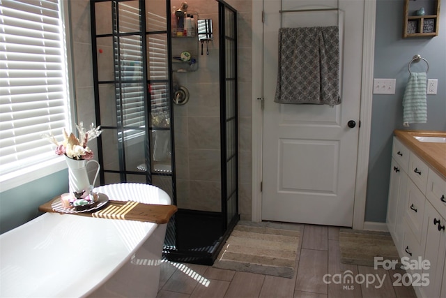 full bathroom featuring vanity, a freestanding tub, a stall shower, and wood tiled floor