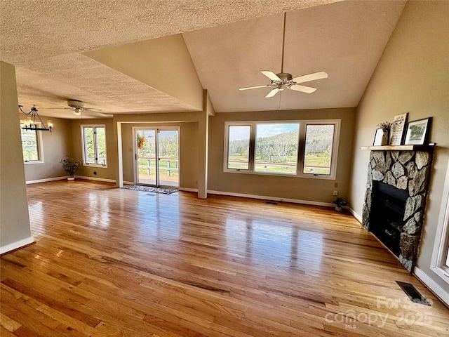 unfurnished living room featuring a fireplace, a textured ceiling, light wood-style floors, and ceiling fan with notable chandelier