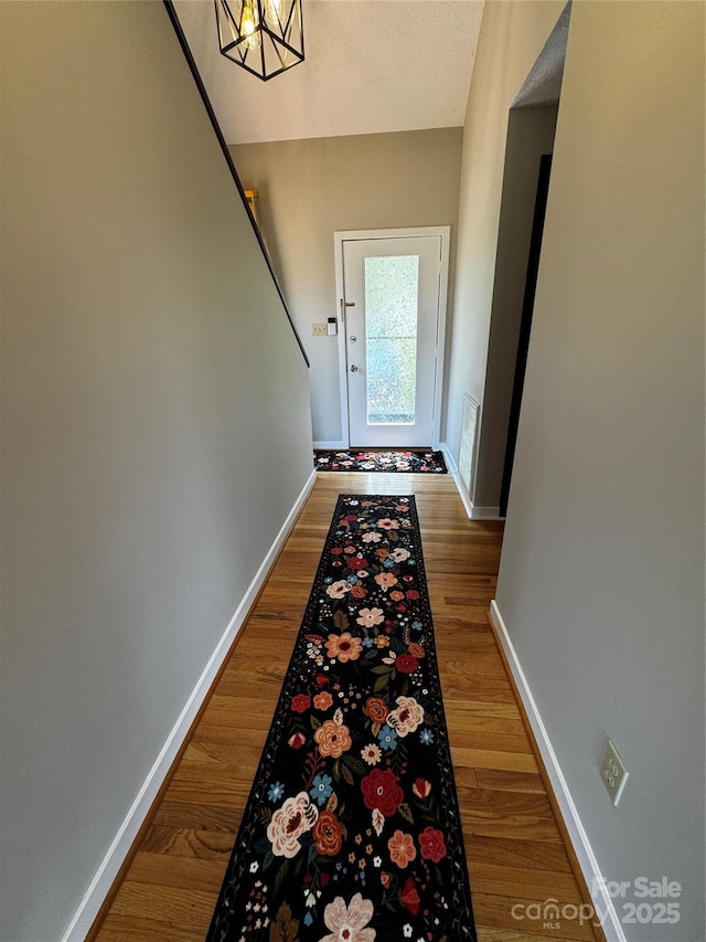 doorway featuring baseboards and wood finished floors