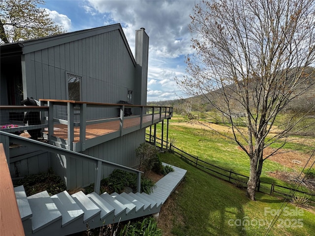 view of property exterior featuring fence, a deck, a yard, and a chimney