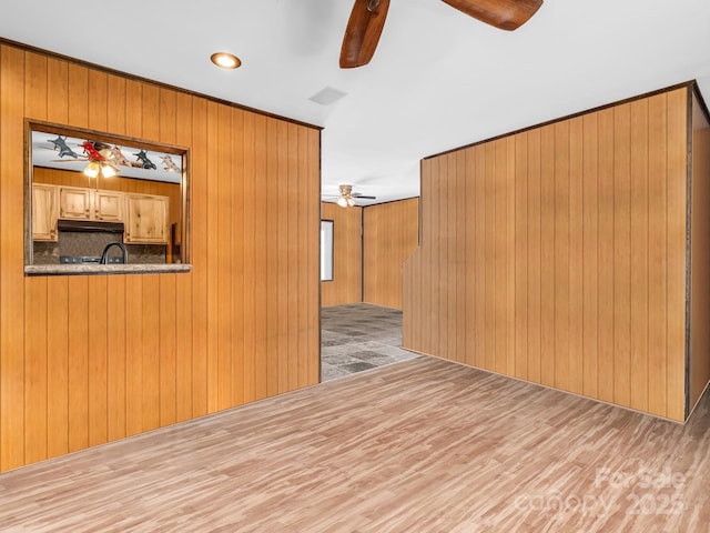 interior space featuring wood finished floors, visible vents, a ceiling fan, and wood walls