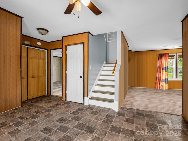 stairs featuring ceiling fan, stone tile floors, visible vents, and wooden walls