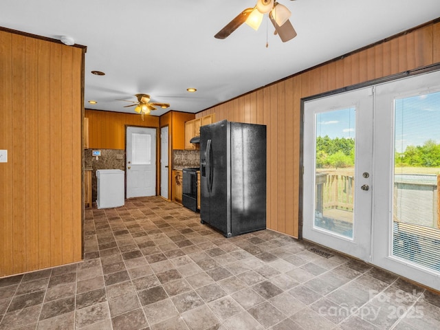 kitchen with stone finish floor, wood walls, ceiling fan, and black appliances