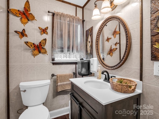 bathroom featuring toilet, crown molding, vanity, and tile walls