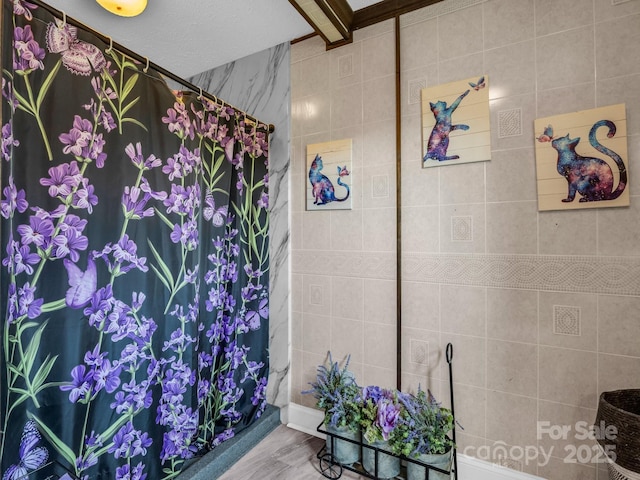 bathroom with a tile shower and tile walls