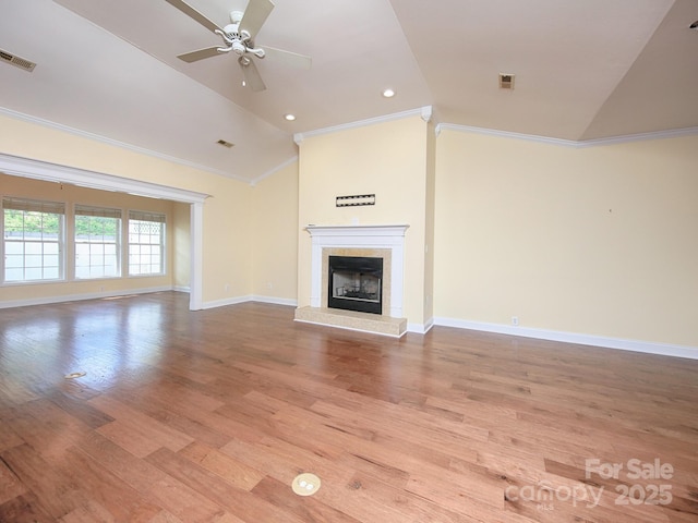 unfurnished living room featuring crown molding, visible vents, vaulted ceiling, a tiled fireplace, and a ceiling fan