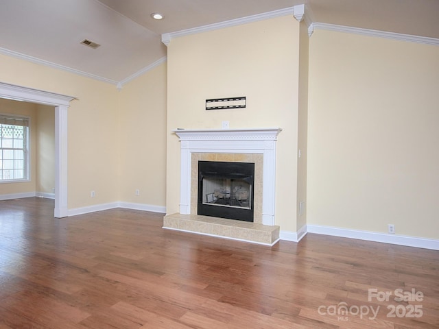 unfurnished living room featuring lofted ceiling, a tile fireplace, wood finished floors, and ornamental molding