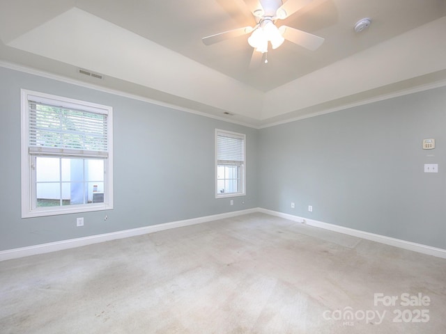spare room featuring crown molding, visible vents, light carpet, and a tray ceiling