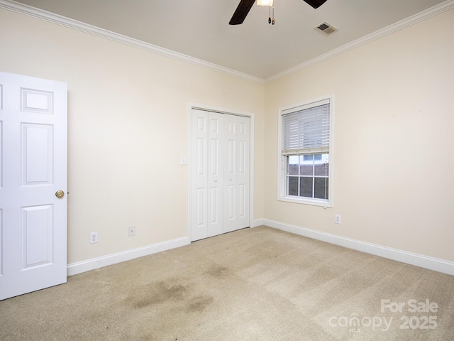 unfurnished bedroom with ornamental molding, visible vents, carpet flooring, and baseboards