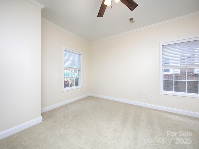 empty room featuring crown molding, light colored carpet, visible vents, baseboards, and a ceiling fan