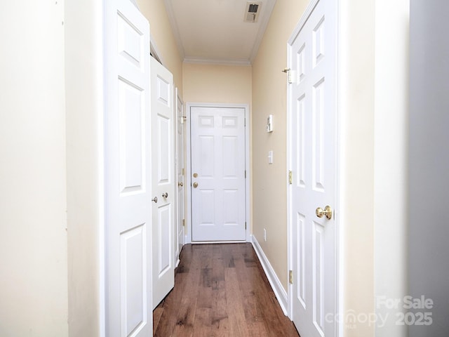hall with baseboards, visible vents, ornamental molding, and dark wood-type flooring