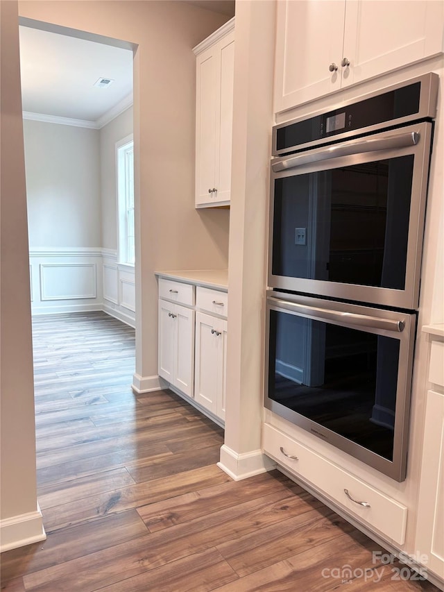 7001 New Town Rd, Waxhaw, NC 28173 - kitchen with double oven, ornamental molding, white cabinets, wood finished floors, and light countertops