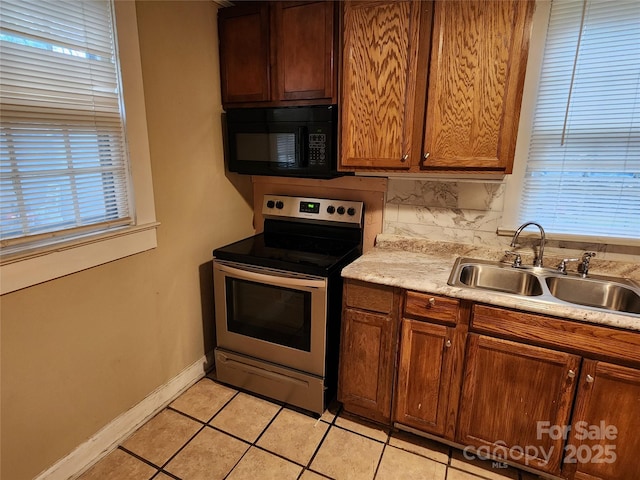 kitchen featuring black microwave, light countertops, backsplash, stainless steel range with electric stovetop, and a sink