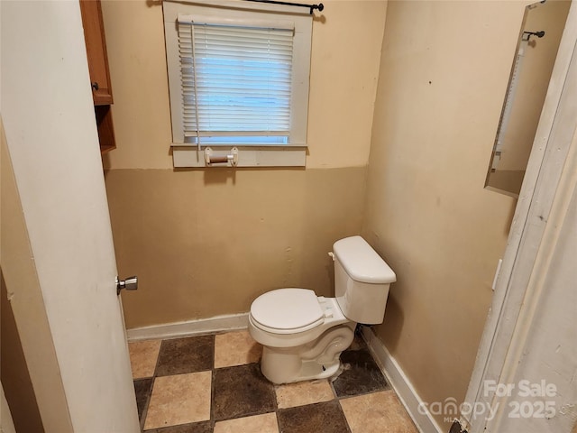 half bath featuring toilet and baseboards