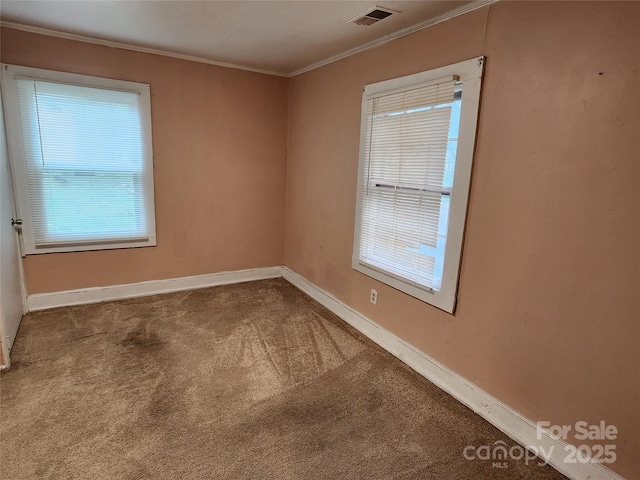 unfurnished room with crown molding, carpet flooring, baseboards, and visible vents