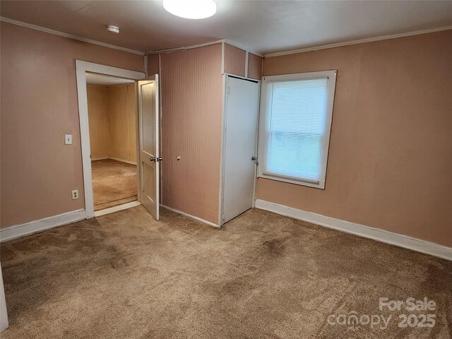 unfurnished bedroom with crown molding, carpet flooring, and baseboards