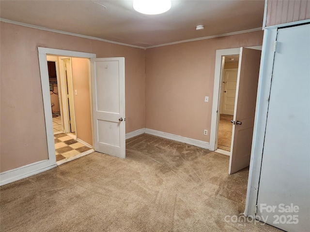 unfurnished bedroom with baseboards, ornamental molding, and carpet