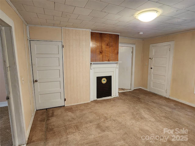 unfurnished living room featuring a fireplace, baseboards, and carpet floors
