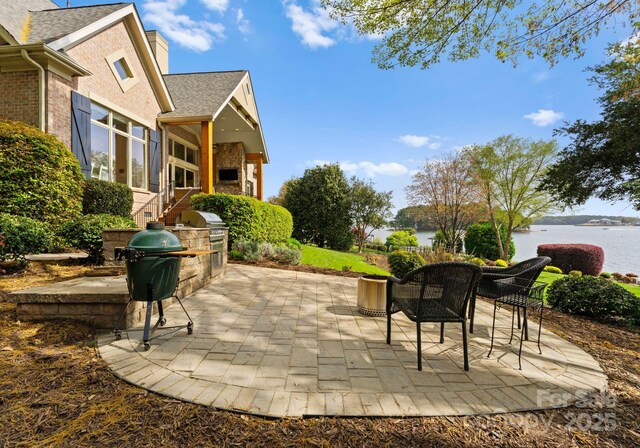 view of patio featuring area for grilling, a water view, and exterior kitchen