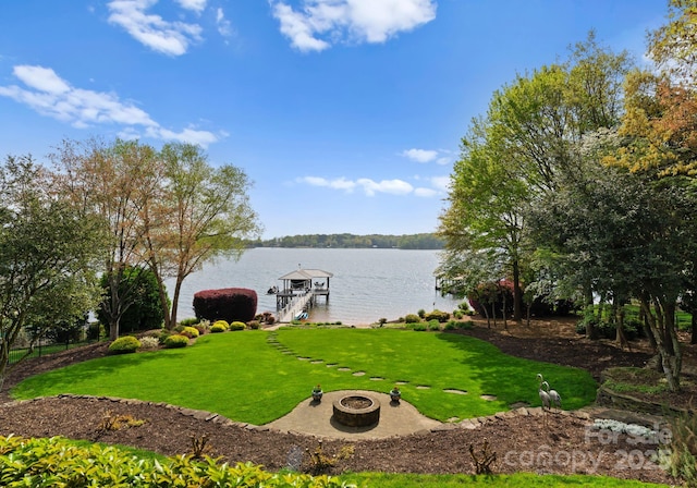 view of yard featuring a fire pit, a boat dock, and a water view