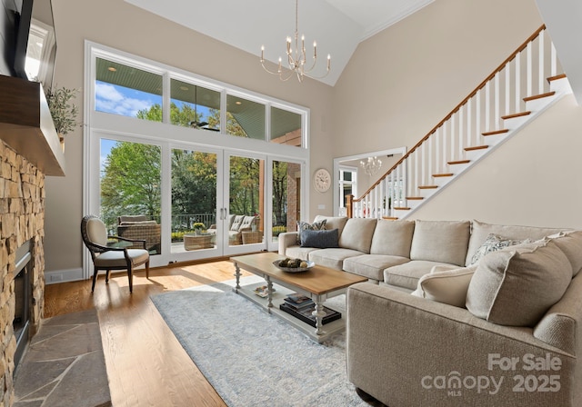 living room with stairs, high vaulted ceiling, a chandelier, and a fireplace