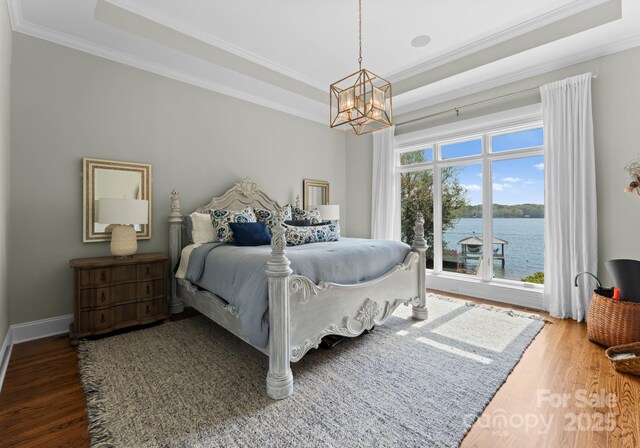 bedroom featuring wood finished floors, a chandelier, crown molding, and a tray ceiling