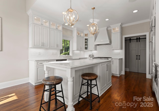kitchen with a kitchen breakfast bar, decorative backsplash, a kitchen island, custom exhaust hood, and a notable chandelier