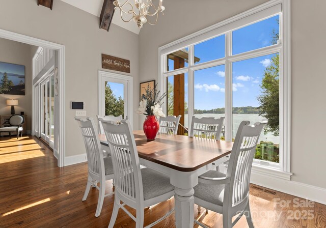 dining room featuring baseboards, visible vents, wood finished floors, and a notable chandelier