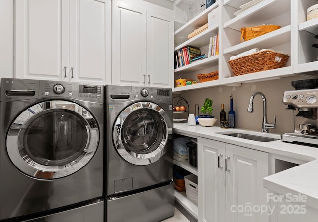 laundry area featuring washing machine and dryer, a sink, and cabinet space
