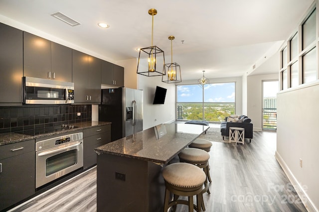 333 W Trade St Unit 1802, Charlotte, NC 28202 - kitchen with backsplash, a kitchen breakfast bar, appliances with stainless steel finishes, light wood-style flooring, and visible vents