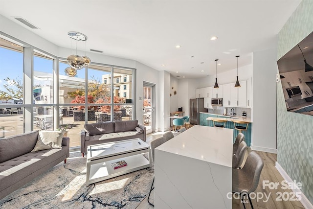 333 W Trade St Unit 1802, Charlotte, NC 28202 - living room featuring visible vents, a chandelier, baseboards, recessed lighting, and light wood-style floors