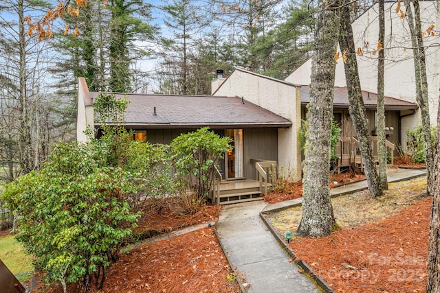 mid-century inspired home featuring a chimney and roof with shingles