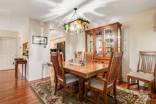 dining space with an inviting chandelier, dark wood-style flooring, and baseboards