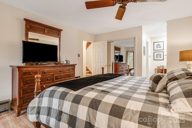 bedroom featuring a baseboard radiator, a ceiling fan, a closet, and light wood-style floors