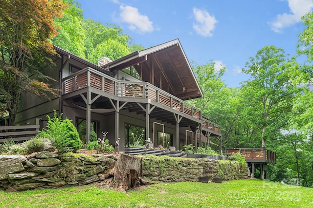 rear view of property with a chimney, a lawn, and stucco siding