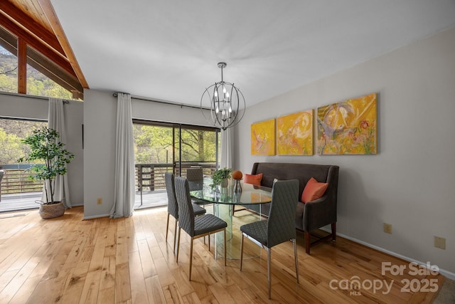 dining space featuring a chandelier, light wood-style floors, lofted ceiling, and baseboards